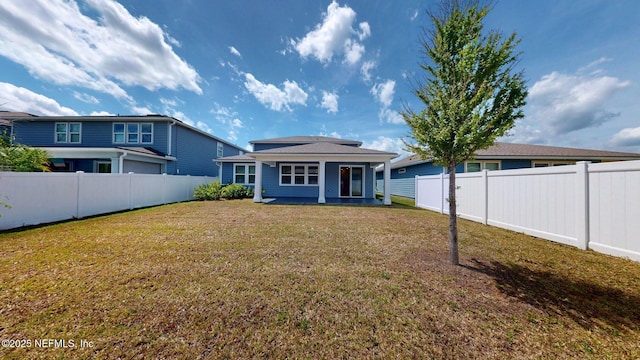 back of house with a yard and a fenced backyard
