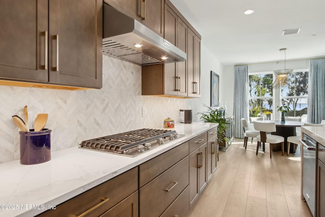 157 Oak Pk Dr, Saint Johns, FL 32259 - kitchen featuring under cabinet range hood, stainless steel appliances, light wood finished floors, backsplash, and light stone countertops