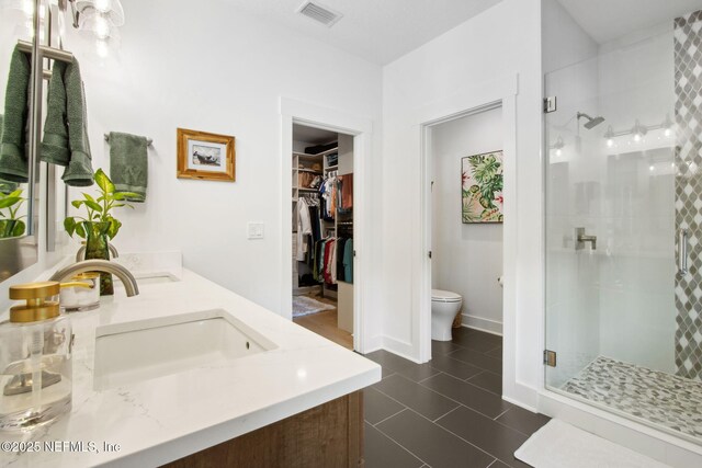 157 Oak Pk Dr, Saint Johns, FL 32259 - bathroom featuring a stall shower, toilet, a spacious closet, double vanity, and tile patterned floors