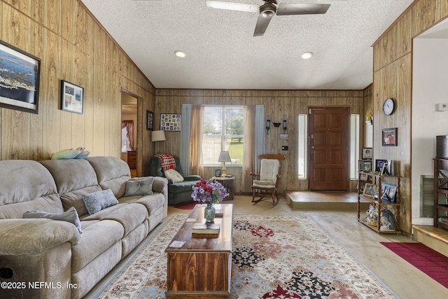 living area with a textured ceiling, wood walls, a ceiling fan, and lofted ceiling