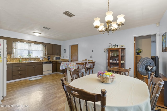 dining area featuring visible vents, light wood-type flooring, and a notable chandelier