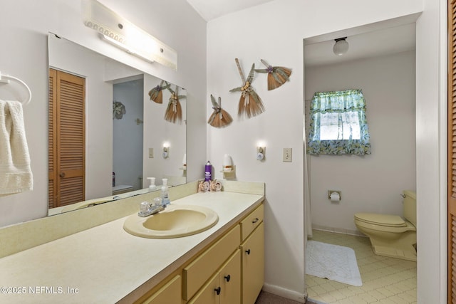 bathroom with toilet, a closet, vanity, and baseboards