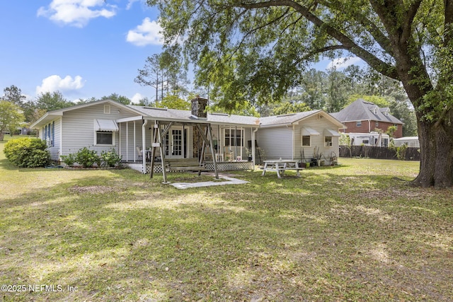 rear view of property featuring fence, a yard, french doors, and a chimney