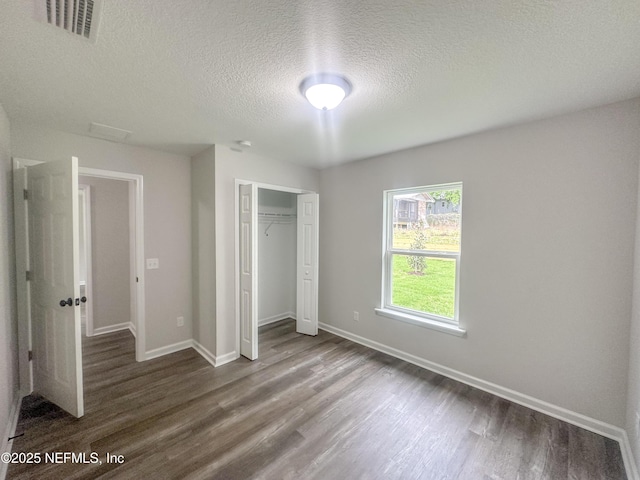 116 Moseley Ave, Palatka, FL 32177 - unfurnished bedroom with dark wood finished floors, a textured ceiling, a closet, and baseboards