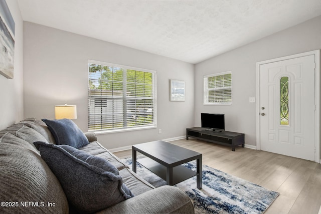 living area featuring light wood-style floors, baseboards, and a textured ceiling