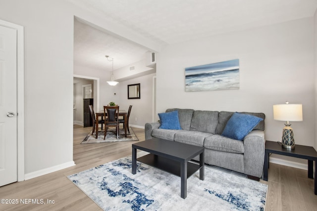 living room featuring light wood-style flooring, baseboards, and visible vents