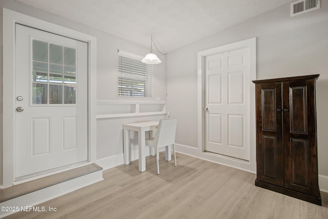 dining space with visible vents, baseboards, light wood-style floors, and a textured ceiling
