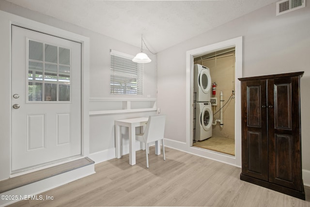 dining room with visible vents, light wood-style flooring, stacked washer / dryer, and baseboards