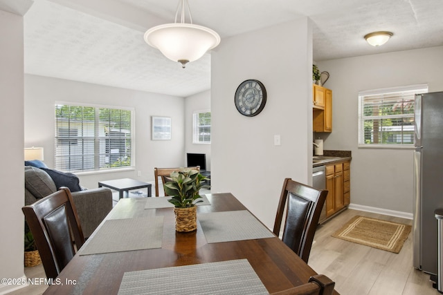 dining space with light wood-style flooring, a wealth of natural light, and baseboards
