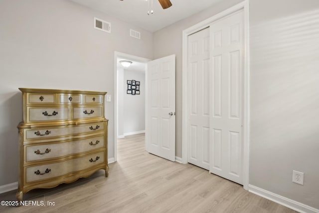bedroom with a closet, light wood finished floors, baseboards, and visible vents