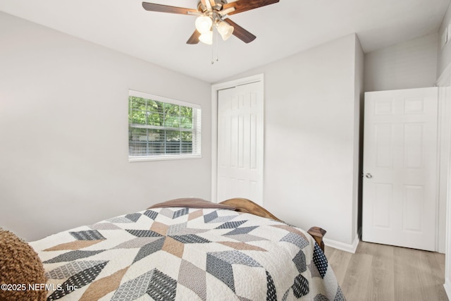 bedroom with light wood-type flooring, a closet, baseboards, and ceiling fan