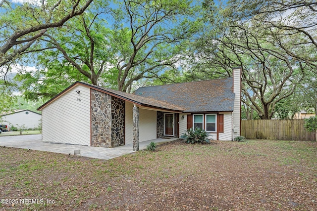view of front of property featuring fence, a chimney, and stone siding
