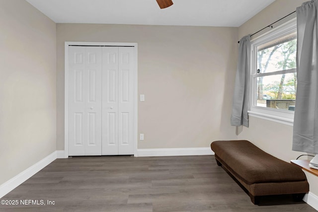 living area with baseboards, wood finished floors, and ceiling fan