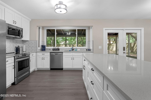 kitchen featuring white cabinets, dark wood-style flooring, decorative backsplash, and appliances with stainless steel finishes