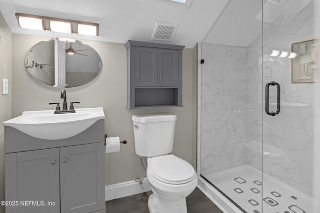 full bath featuring vanity, baseboards, a stall shower, toilet, and visible vents