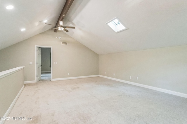 additional living space featuring vaulted ceiling with skylight, light colored carpet, a ceiling fan, and visible vents