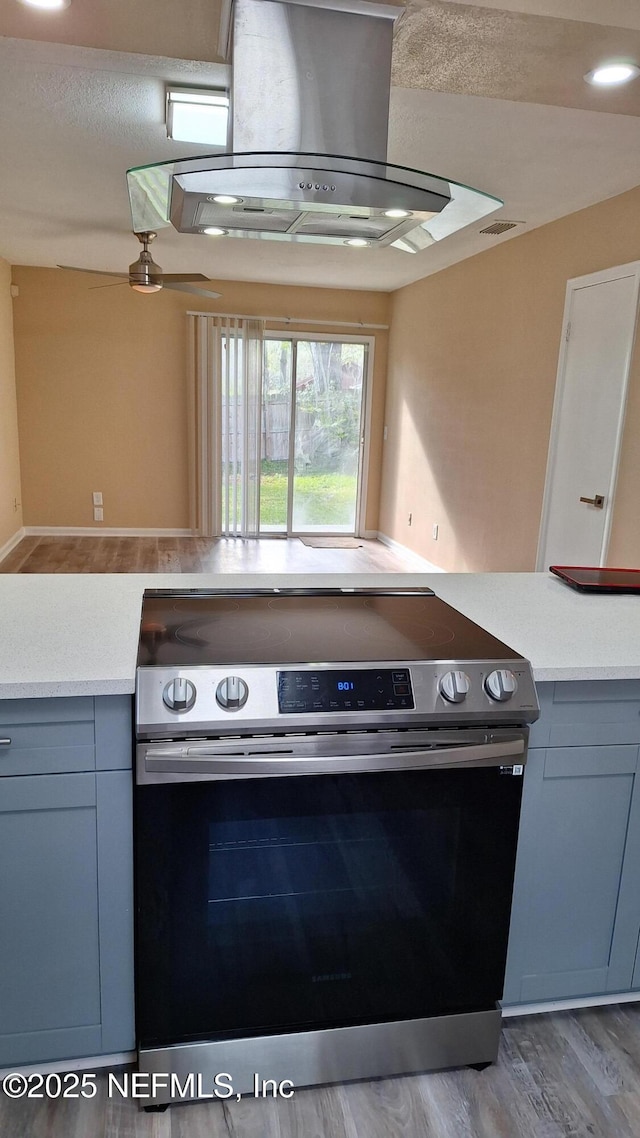 2756 Hidden Village Dr, Jacksonville, FL 32216 - kitchen with light countertops, stainless steel electric range oven, island exhaust hood, and gray cabinets