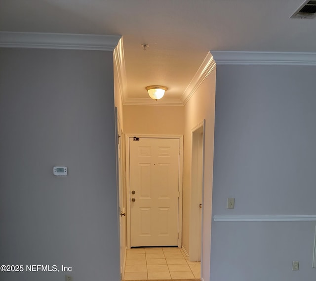 corridor featuring light tile patterned flooring, visible vents, baseboards, and ornamental molding