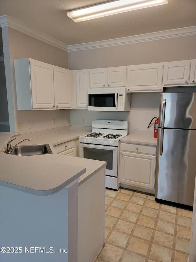 kitchen featuring white cabinets, a peninsula, a sink, white appliances, and ornamental molding
