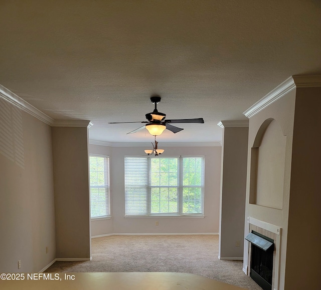 unfurnished living room with carpet floors, crown molding, baseboards, a tiled fireplace, and ceiling fan