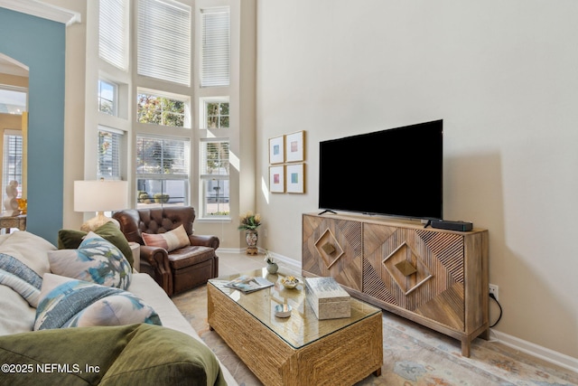 living area with a towering ceiling, arched walkways, and baseboards