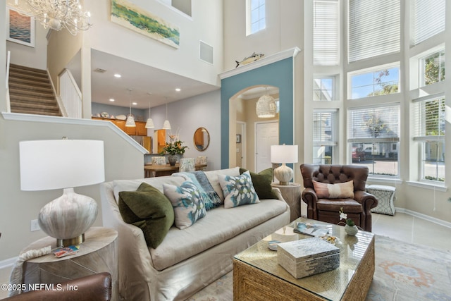 tiled living room featuring a chandelier, visible vents, arched walkways, and a high ceiling