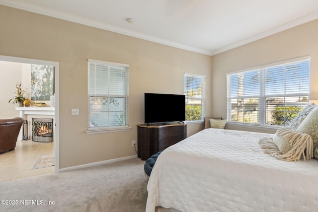 bedroom with crown molding, carpet, a lit fireplace, and baseboards