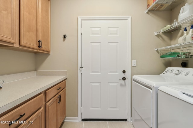 laundry room with light tile patterned floors, washing machine and clothes dryer, and cabinet space