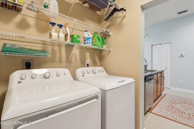 laundry area featuring visible vents, light tile patterned floors, separate washer and dryer, and a sink