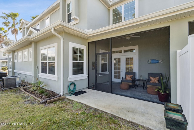 view of exterior entry featuring cooling unit, a ceiling fan, stucco siding, and french doors