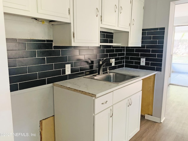 5133 Palmer Ave, Jacksonville, FL 32210 - kitchen featuring a sink, backsplash, light wood-style flooring, and white cabinets