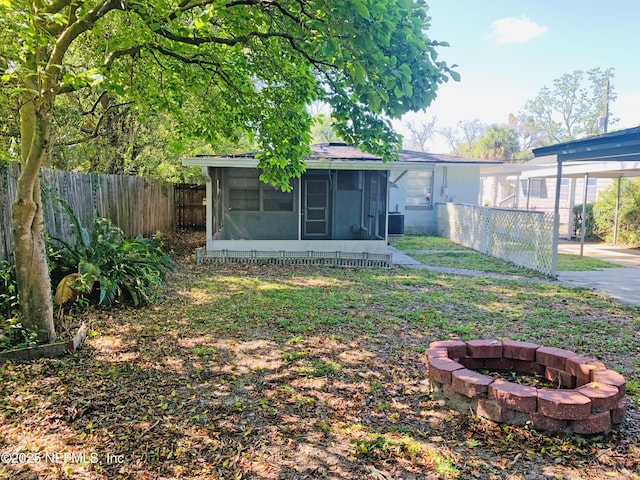 5133 Palmer Ave, Jacksonville, FL 32210 - view of yard featuring fence private yard, a sunroom, a carport, and an outdoor fire pit