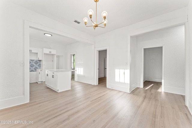 unfurnished living room with a chandelier, visible vents, baseboards, and light wood-style flooring