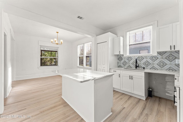 kitchen with a chandelier, white cabinetry, visible vents, and light wood-style flooring