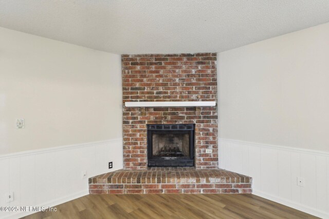 2566 Sandlewood Cir, Orange Park, FL 32065 - unfurnished living room featuring a brick fireplace, a wainscoted wall, and wood finished floors