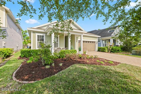view of front of house with concrete driveway, a front lawn, an attached garage, and covered porch