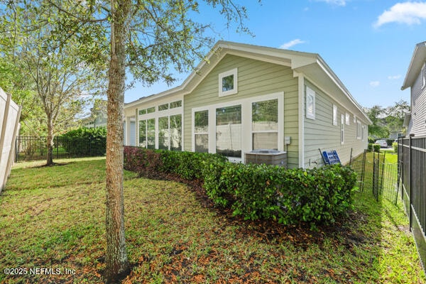 back of property featuring central AC, a fenced backyard, and a lawn