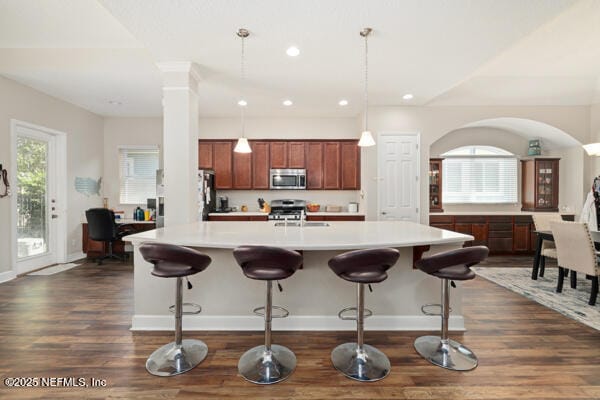 kitchen featuring light countertops, appliances with stainless steel finishes, a kitchen breakfast bar, dark wood-style floors, and recessed lighting