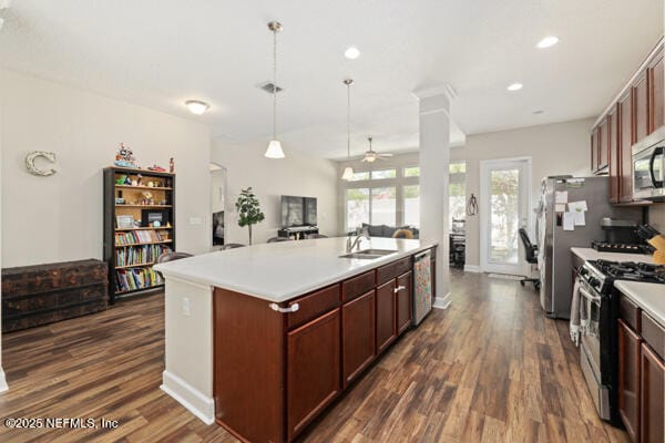 kitchen featuring a sink, open floor plan, ceiling fan, appliances with stainless steel finishes, and dark wood-style floors