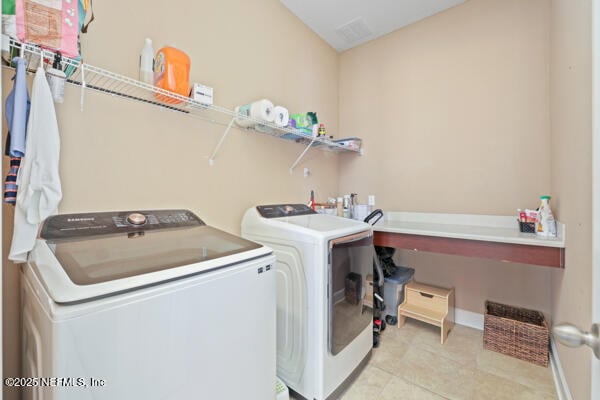 laundry area with light tile patterned floors, separate washer and dryer, laundry area, and baseboards