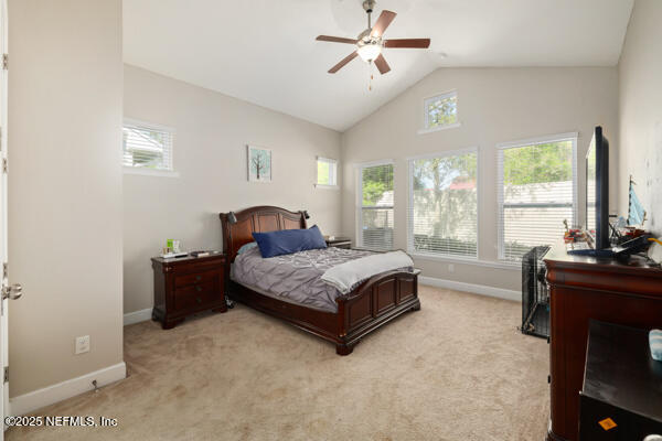 bedroom with light carpet, ceiling fan, baseboards, and lofted ceiling