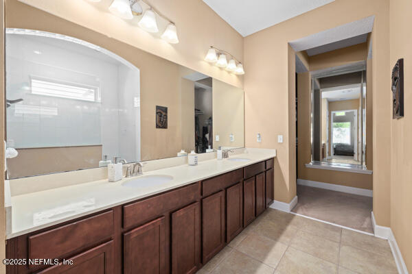 bathroom featuring tile patterned floors, double vanity, baseboards, and a sink