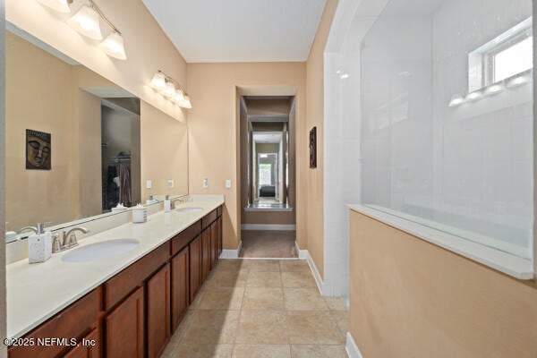 full bath with double vanity, a sink, tile patterned flooring, and baseboards