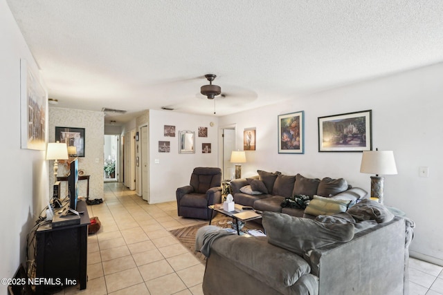 living area with light tile patterned floors, a ceiling fan, visible vents, and a textured ceiling
