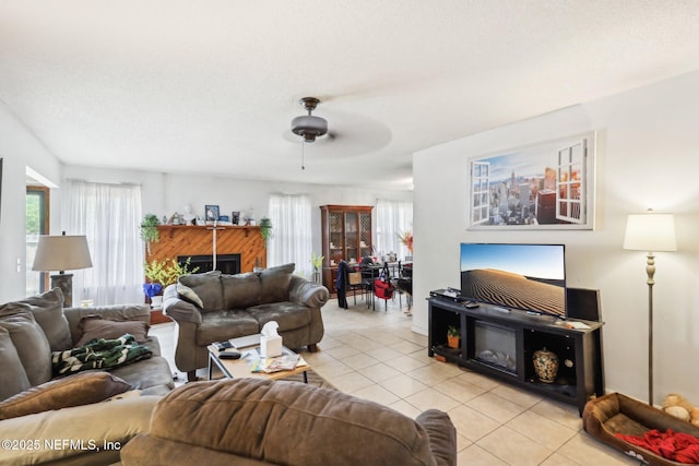 living area with a fireplace, ceiling fan, and light tile patterned flooring