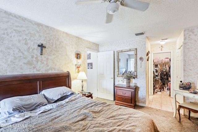 carpeted bedroom with a textured ceiling, wallpapered walls, visible vents, and tile patterned floors