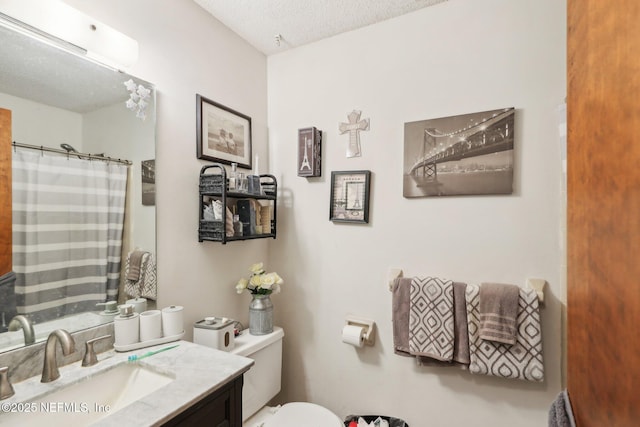 bathroom with toilet, a shower with shower curtain, vanity, and a textured ceiling