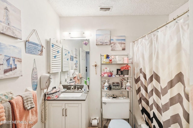 bathroom featuring visible vents, toilet, vanity, and a textured ceiling