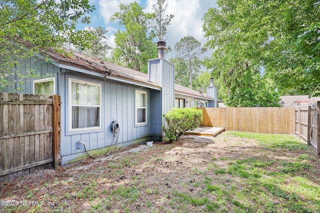 exterior space with board and batten siding, a fenced backyard, and a chimney