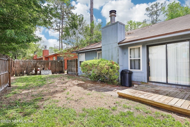 rear view of house featuring a fenced backyard, a wooden deck, and a chimney